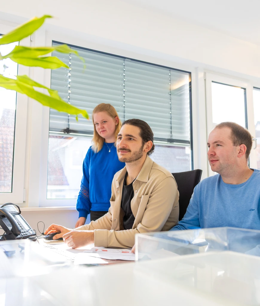 Drei Mitarbeitende im Büro an einem Schreibtisch